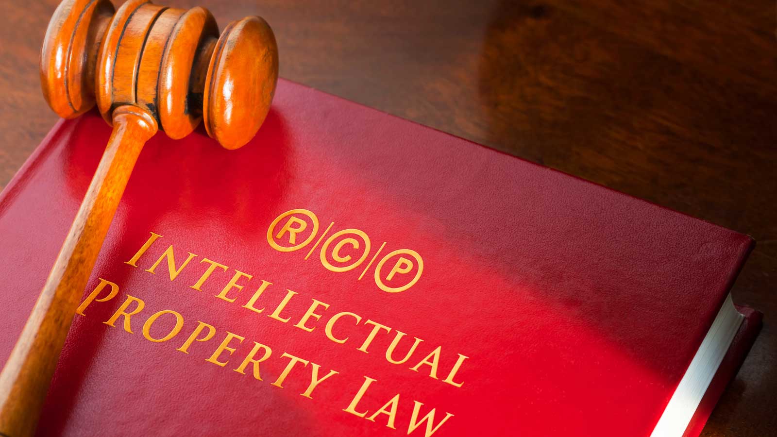 A wooden gavel rests on a red book labeled _Intellectual Property Law