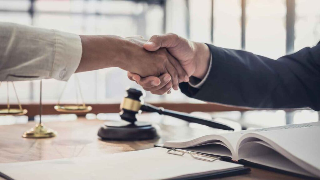 Two individuals shaking hands in a law firm office.