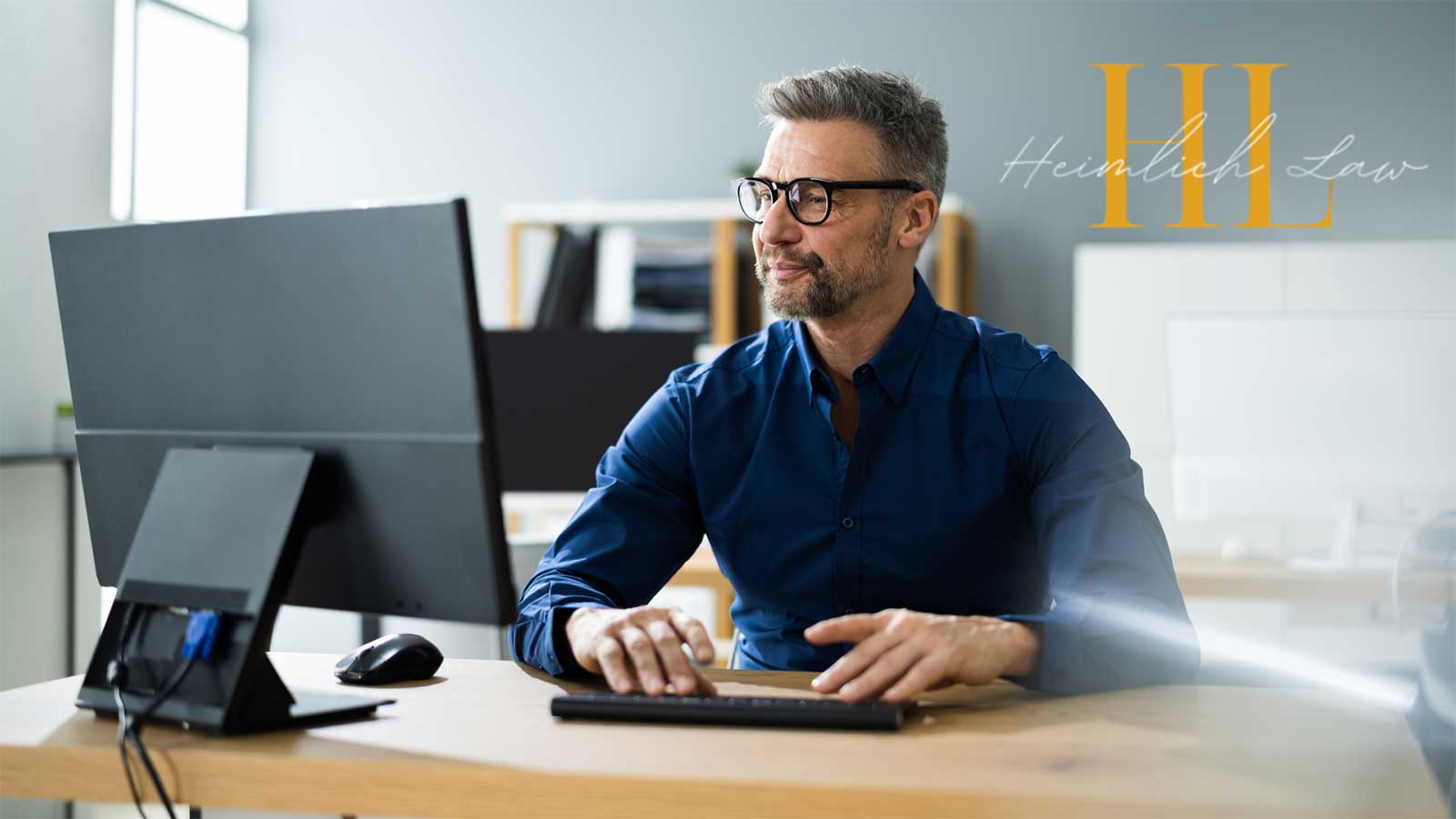 A man sitting at his desk in front of a computer, focused on his work